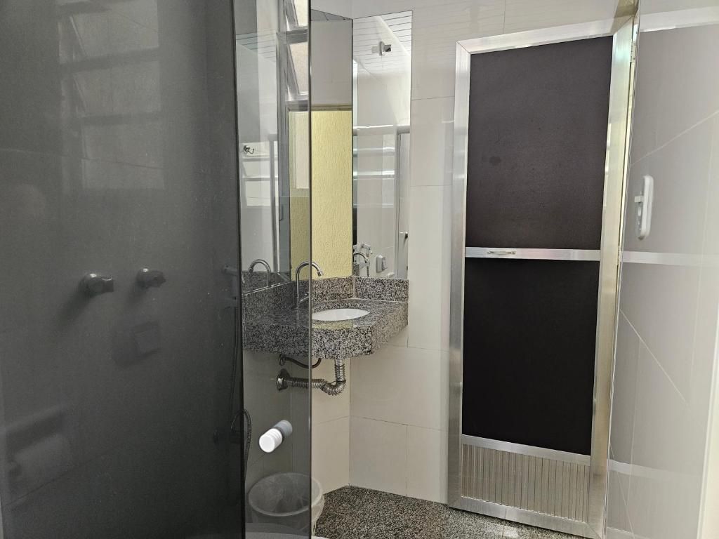 A bathroom with a glass door, a granite countertop sink, and a mirror.