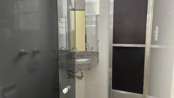 A bathroom with a glass door, a granite countertop sink, and a mirror.