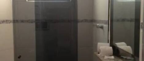 A bathroom with a glass shower enclosure, a sink with a mirror, and a toilet.