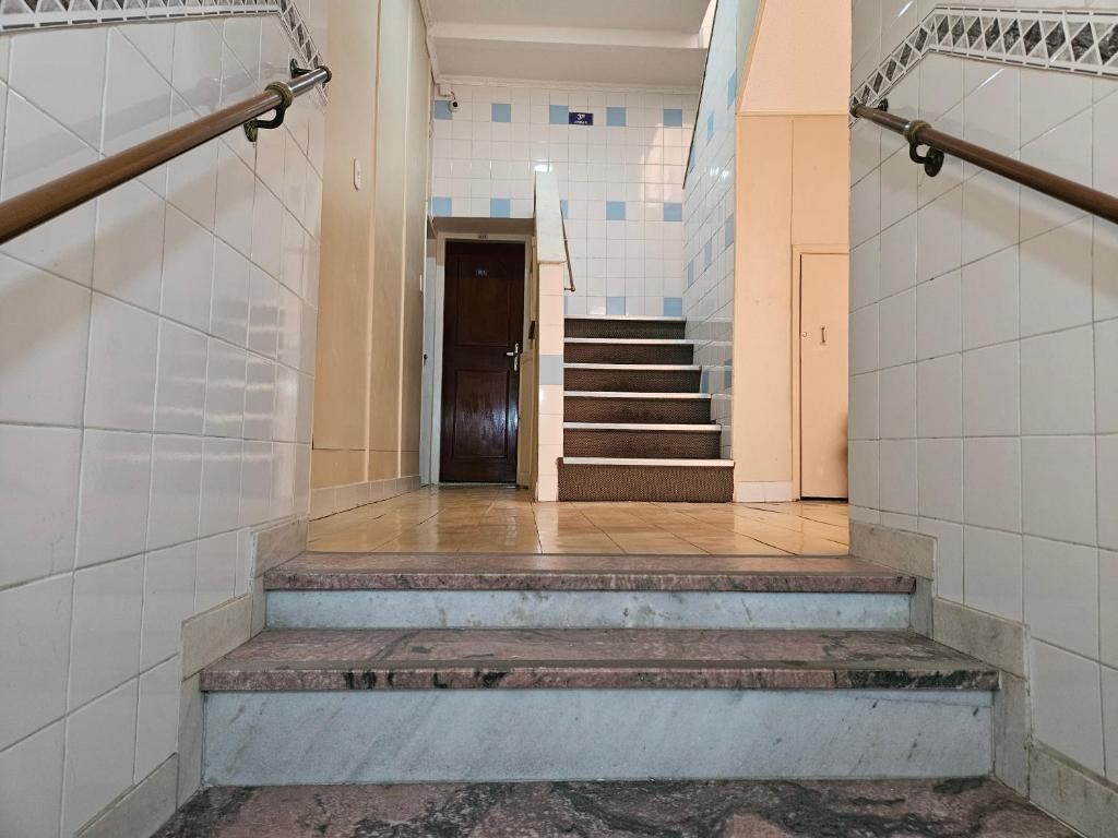 A staircase with marble steps and metal handrails, leading to a door at the top.
