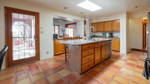 Una cocina con una isla central, armarios de madera y piso de baldosas.