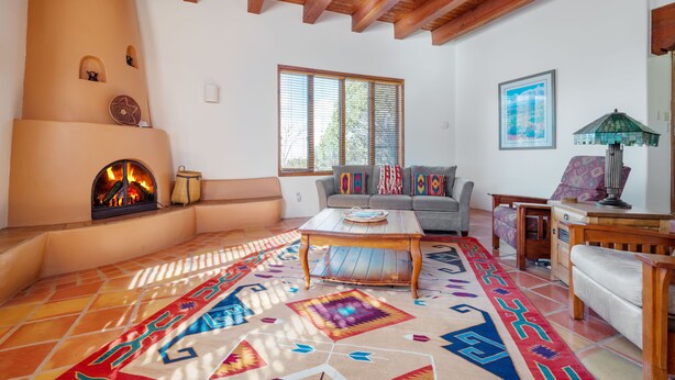 Una sala de estar acogedora con chimenea, un sofá, una mesa de centro y una alfombra colorida.