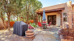 Un patio al aire libre con una parrilla cubierta, un barril de madera y un comedor con sillas y una mesa.