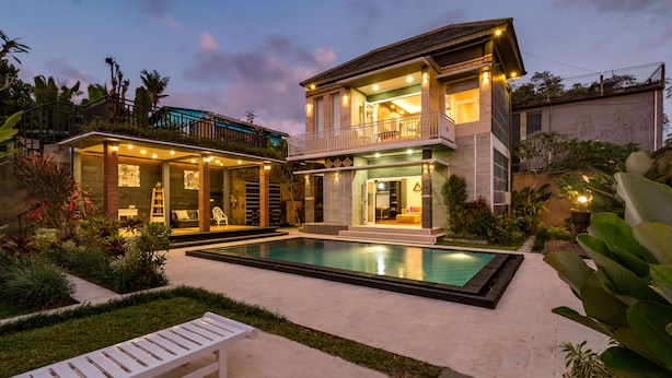 Una casa de dos pisos con piscina, balcón y un jardín bien cuidado.