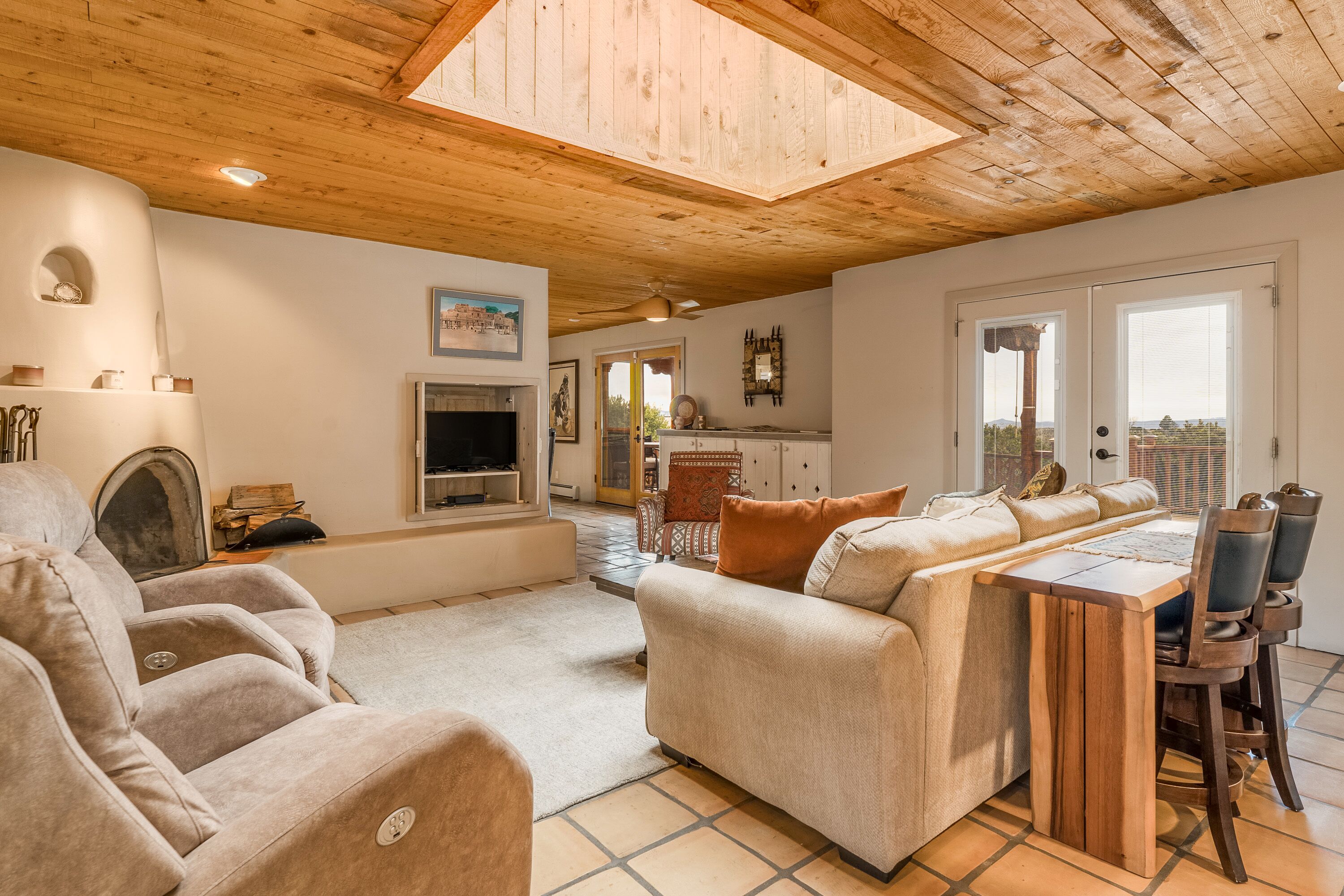 Un vaste espace de vie doté d’un haut plafond, d’une cheminée, d’un téléviseur et d’un coin repas avec une table et des chaises en bois.
