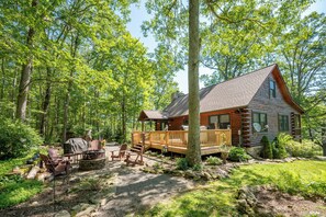 A log cabin with a deck, surrounded by a forest. - Woodsy Retreat w/ Fireplace, Hot Tub & Fire Pit (McHenry)