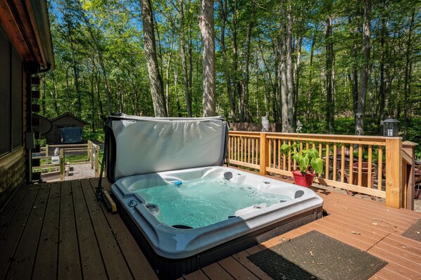 Un jacuzzi en una terraza de madera con vista a un bosque.