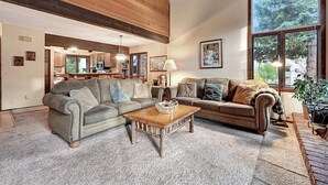 A cozy living room with a fireplace, a dining area, and a kitchen visible through an open door. - Sunrise 35: Spacious, quiet (Mammoth Lakes)