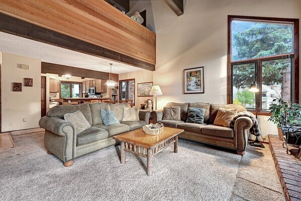 A cozy living room with a fireplace, a dining area, and a kitchen visible through an open door. - Sunrise 35: Spacious, quiet (Mammoth Lakes)