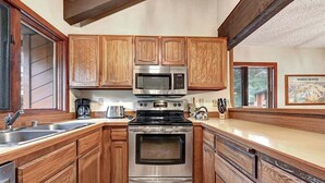 A kitchen with wooden cabinets, a stainless steel microwave, a stove, and a sink. - Sunrise 35: Spacious, quiet (Mammoth Lakes)