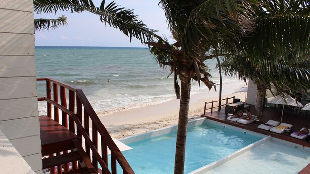 Un área junto a la piscina con cubierta de madera, piscina y vista a la playa y al océano.