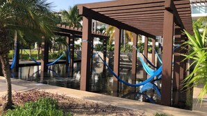 Un área de piscina con pérgolas de madera y hamacas azules.