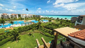 Un resort con varias piscinas, palmeras y vista al océano.