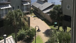 A view of a waterfront property with multiple buildings, including a large building with a balcony and a smaller structure with a covered patio. - Fishing, Golf & Beach Getaway! (Carrabelle)