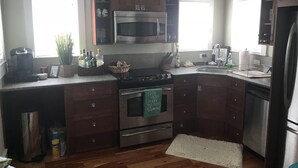 A kitchen with dark wooden cabinets, stainless steel appliances, and a window providing natural light. - Fishing, Golf & Beach Getaway! (Carrabelle)