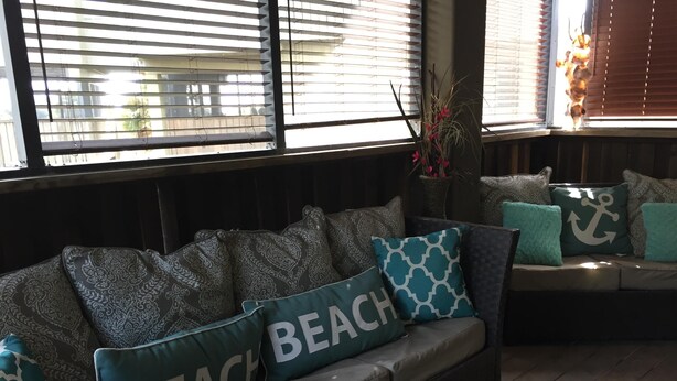 A cozy seating area with a sofa and a bench, adorned with patterned cushions and a 'BEACH' pillow. - Fishing, Golf & Beach Getaway! (Carrabelle)