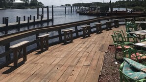 A wooden deck with benches and tables overlooking a calm body of water, docks, and boats. - Fishing, Golf & Beach Getaway! (Carrabelle)