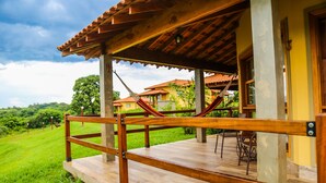A wooden deck with a hammock, a table, and chairs.