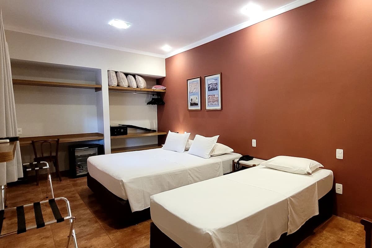 Habitación de hotel pequeña con dos camas individuales, un escritorio y una silla.