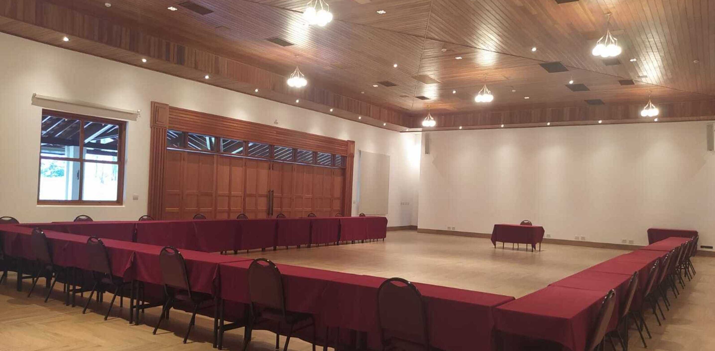 A conference room with a long table and chairs, wooden ceiling, and large windows.
