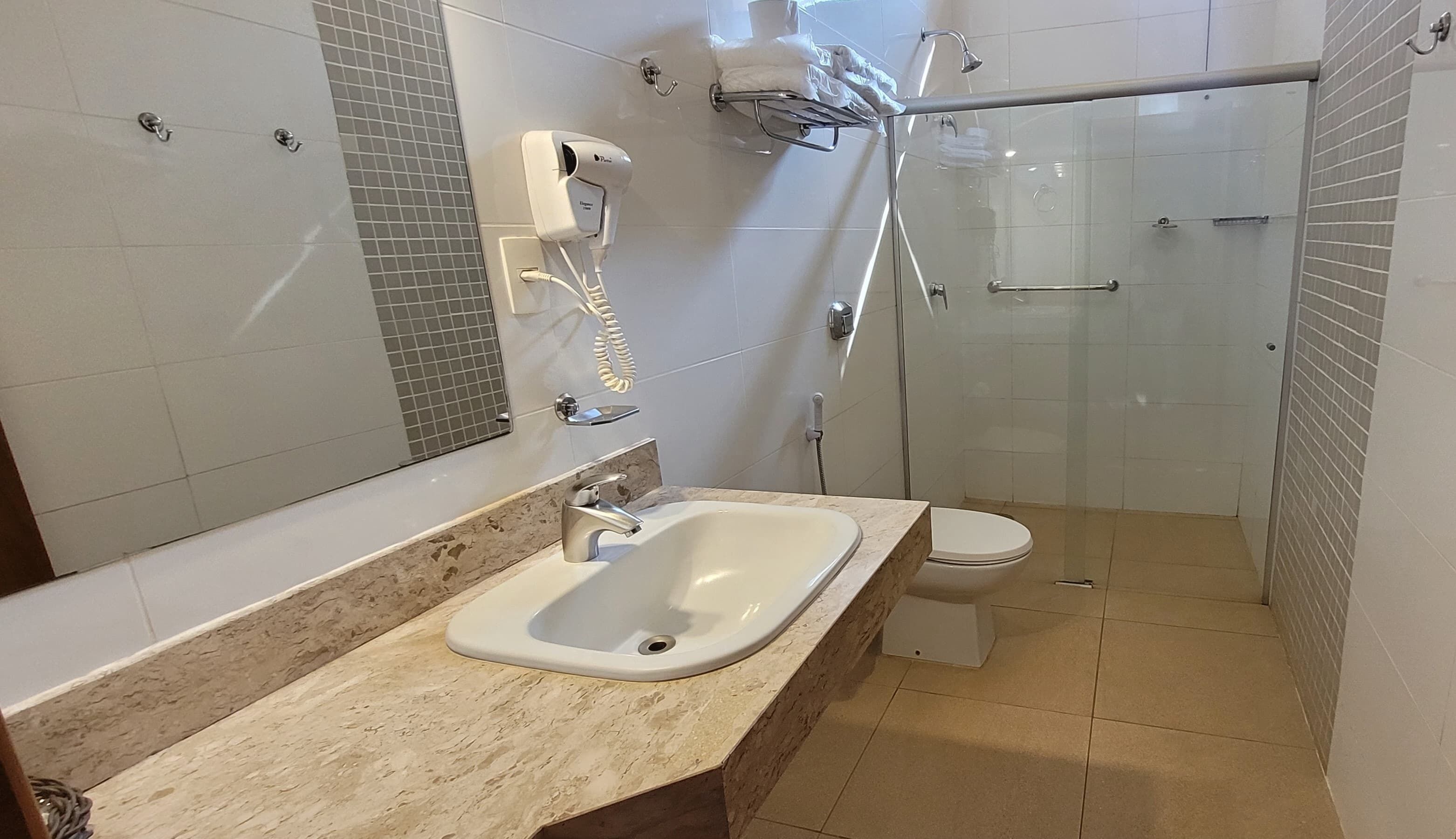 Un baño con lavamanos, inodoro y ducha con mampara de vidrio.