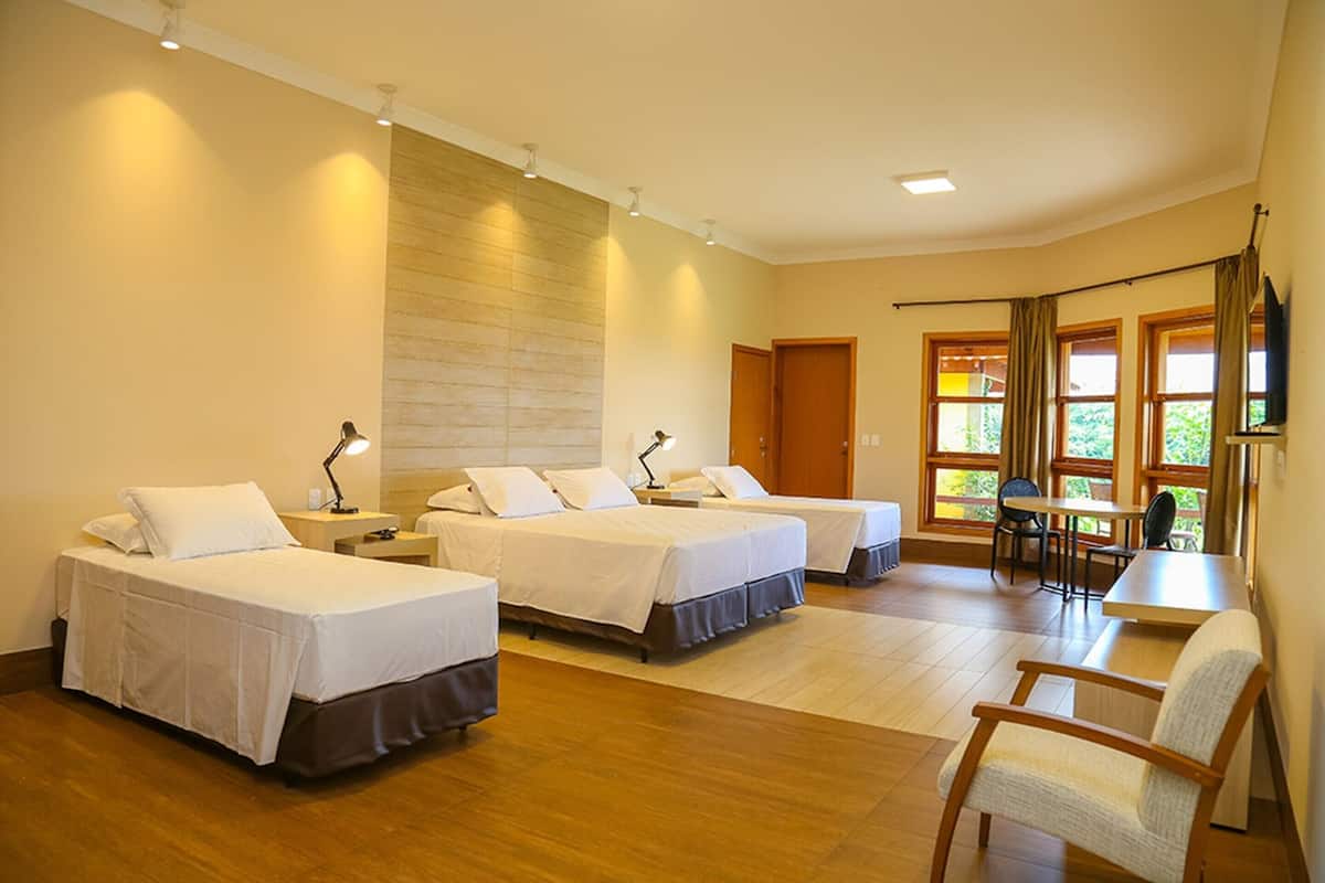 Una habitación de hotel con tres camas individuales, un escritorio y una silla.