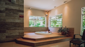 A spa area with a hot tub, wooden steps, and a chair.