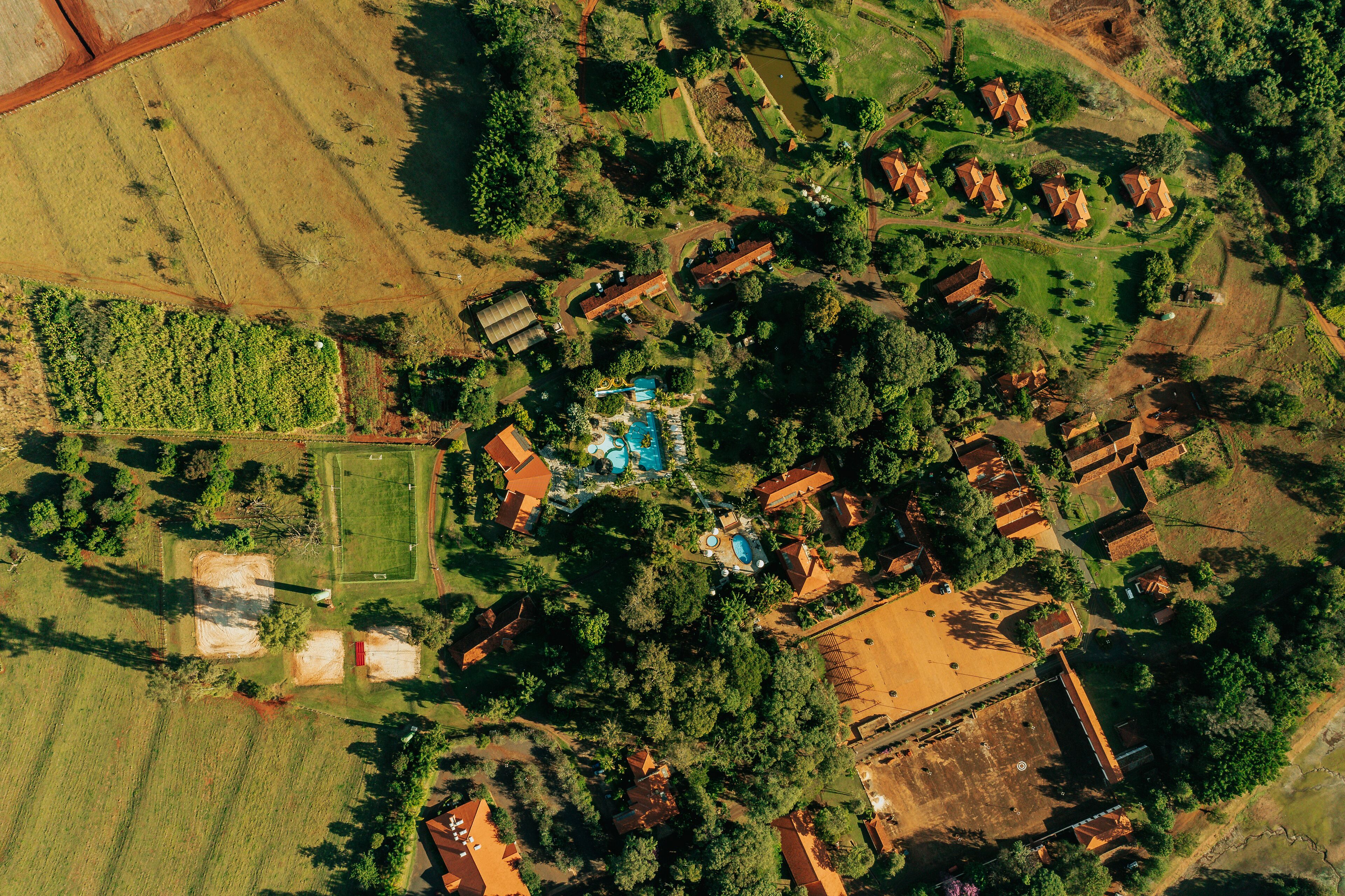 Vista aérea de una zona residencial con varias casas, una piscina y follaje circundante.