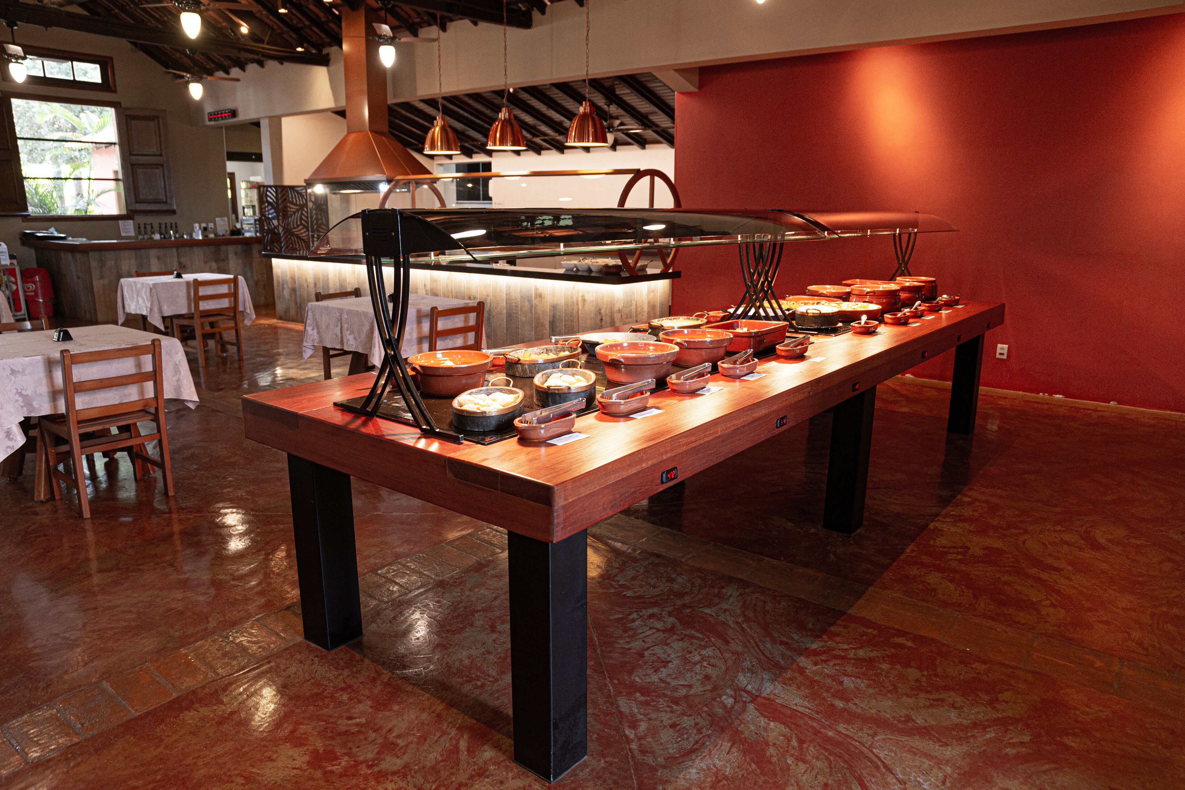 A buffet setup with multiple serving stations and a bar area in the background.