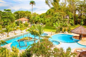 A large outdoor swimming pool surrounded by lush greenery and palm trees. - Hotel Fazenda Salto Grande (Araraquara)
