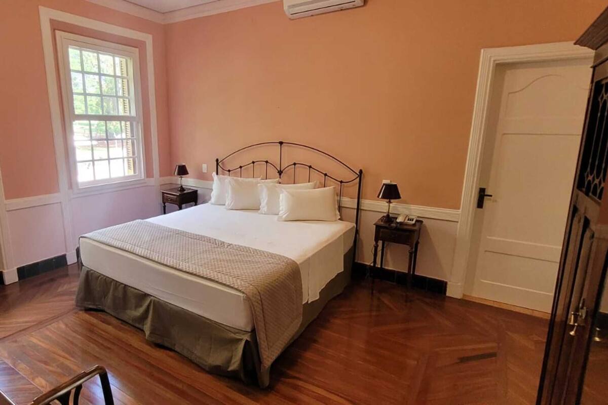 Un dormitorio con una cama, dos mesitas de noche, una ventana y una puerta.