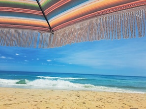 A beach with a colorful umbrella and a clear view of the ocean. - Oceanfront 6BR, 5BA Corolla retreat with beach access, hot tub, and pool. WH-39 (Corolla)