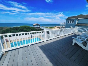 A wooden deck with a pool, white railings, and a view of the ocean. - Oceanfront 6BR, 5BA Corolla retreat with beach access, hot tub, and pool. WH-39 (Corolla)