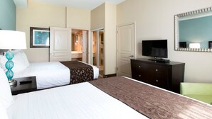 A hotel room with two beds, a TV, a dresser, and a mirror.