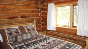 Une chambre dans un chalet en rondins, avec un lit, des rideaux et une fenêtre.