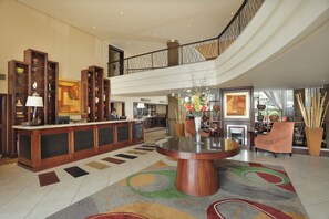 A spacious lobby with a reception desk, a large round table, and a staircase leading to an upper level. - Stayeasy Rustenburg (Rustenburg)