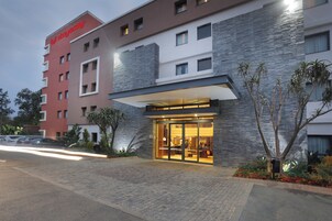 Un hotel con fachada moderna, amplia entrada de vidrio y un letrero visible.