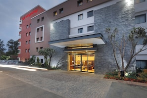 Um hotel com fachada moderna, ampla entrada de vidro e placa visível.
