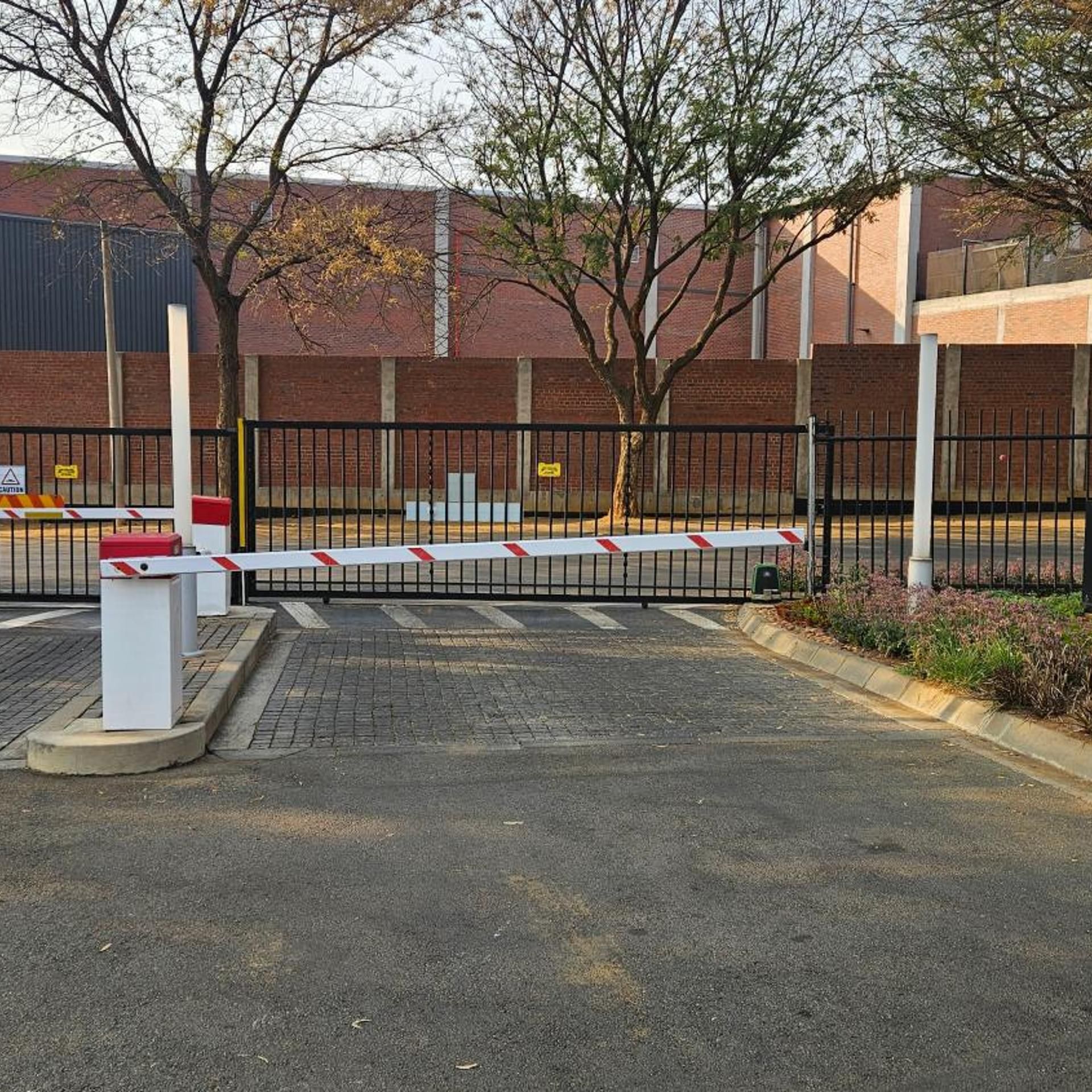 A gated parking area with a brick building in the background.