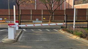 A gated parking area with a brick building in the background.