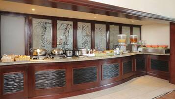 A buffet setup with various food items and kitchen appliances.