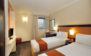 A hotel room with two beds, a desk, a TV, a window with curtains, and a view of the outside. - Stayeasy Rustenburg (Rustenburg)