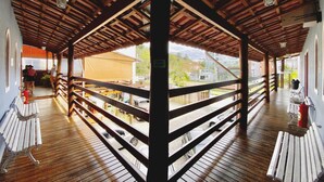 A covered outdoor area with wooden flooring, metal railings, and benches. - Pousada Beija Flor (Ubatuba)