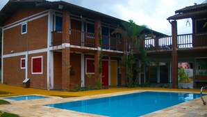 A two-story building with a swimming pool, brick exterior, and balconies. - Pousada Beija Flor (Ubatuba)