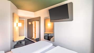 A hotel room with a bed, a TV mounted on the wall, and a mirror.