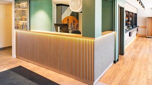 A reception area with a modern design, featuring a bar and a counter with a logo. - B&B HOTEL Hannover-Laatzen (Laatzen)