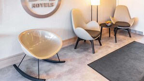 Une chambre d’hôtel de type «
bed and breakfast
» avec une chaise moderne, deux fauteuils, une petite table sur laquelle se trouve un saladier rempli de fruits et une lampe.