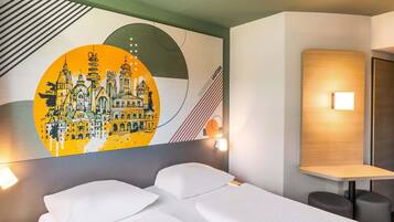 A hotel room with a bed, two bedside tables, a wall-mounted light, and a mural depicting a cityscape.