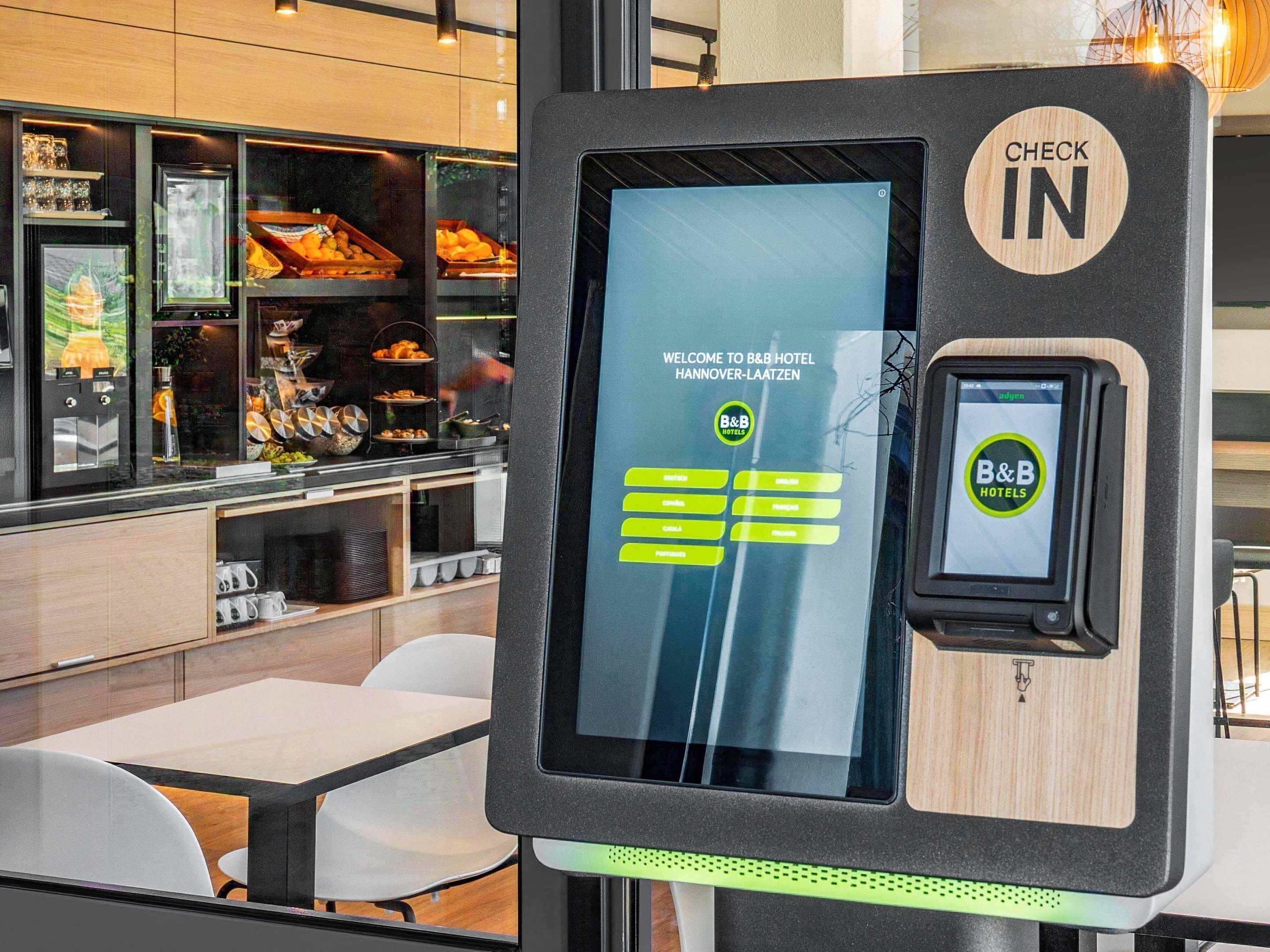 A self-service check-in kiosk at B&B Hotel in Hannover-Laazzen with a digital display and a card reader.