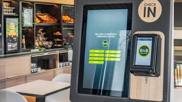 A self-service check-in kiosk at B&B Hotel in Hannover-Laazzen with a digital display and a card reader.